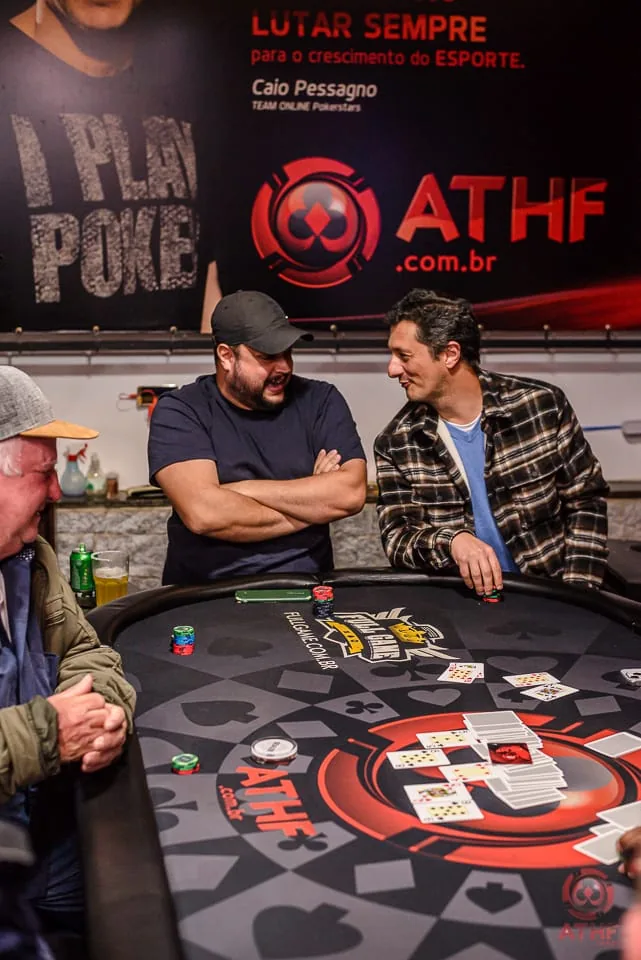 Salão da ATHF com a parede I Play Poker e jogadores na mesa